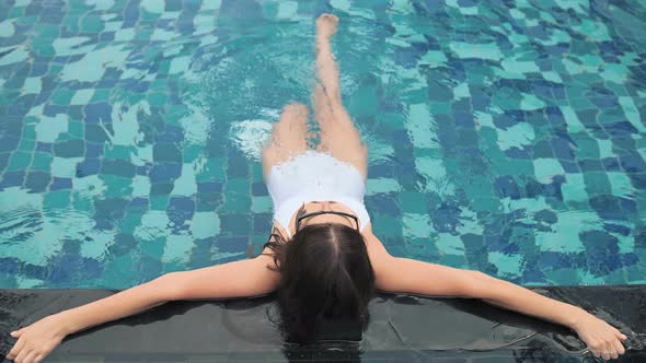 Fashion Woman in White Swimsuit Lying in Swimming Pool