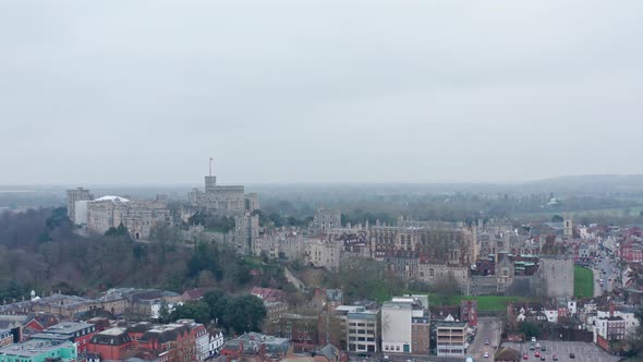 cinematic rotating aerial drone shot of Windsor castle from Eton on a cloudy day