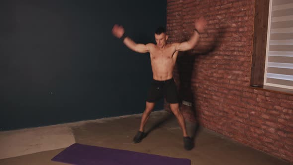 Young Muscular Man in Black Shorts Without Tshirt Training Indoors and Doing Exercise Jumping Jack