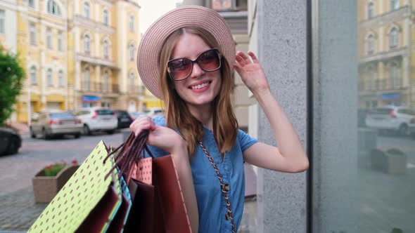 Young Woman with Shopping Bags Walking in a City at Summer Day