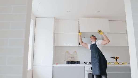 Carpenter installing furniture in new house, repairing and assembling cabinet at the modern kitchen