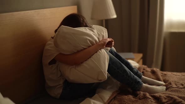 Closeup of Upset Little Girl Crying Sitting Alone in Fetal Position Hiding Face and Rocking on Bed