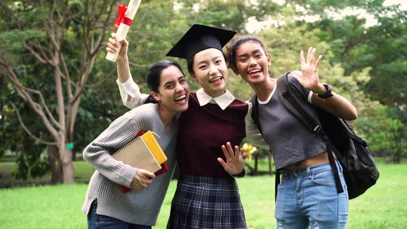 Young Female Graduate and Her Friends Waving Hands at Graduation Ceremony