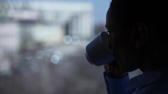 Silhouette of Woman's Face Drinking Tea By Window