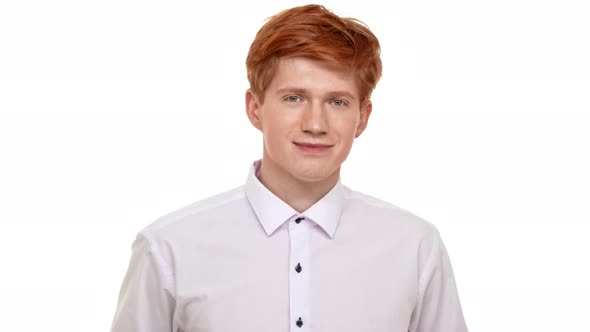 Handsome Young Calm Redhead Caucasian Man Calmly Standing on White Background and Smiling at Camera