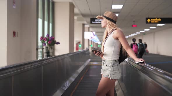 Young Traveler with Straw Hat Standing Sideways in the Airport's Walkway