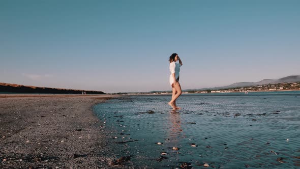Woman walks barefoot on the beach