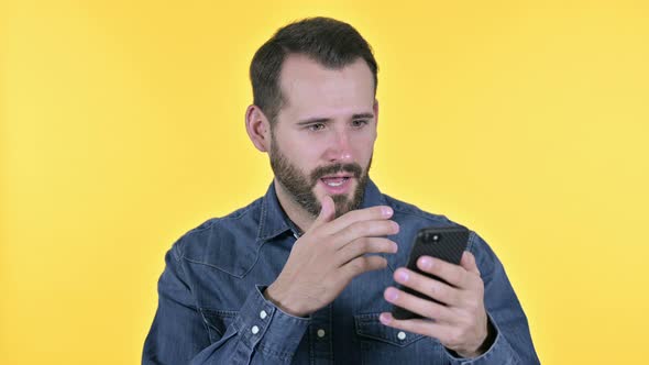 Beard Young Man Celebrating Success on Smartphone, Yellow Background