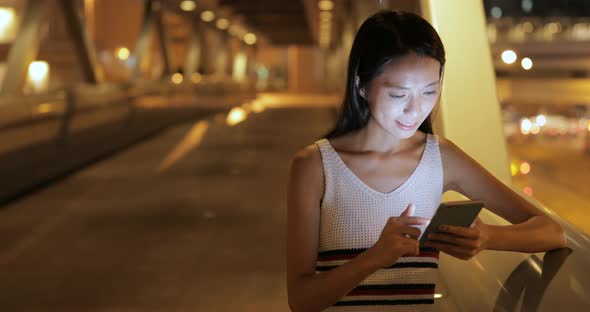 Woman looking at mobile phone in the city at night 