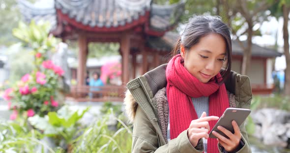 Young asian woman using smart phone in china, beautiful chinese pavilion garden