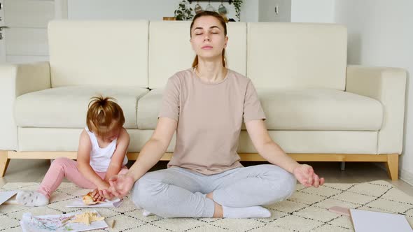 Mom Doing Yoga Exercise at Home for Stress Relief Relaxing While Her Child Little Daughter Distracts