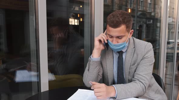 Freelance Businessman in a Mask Working in a Cafe