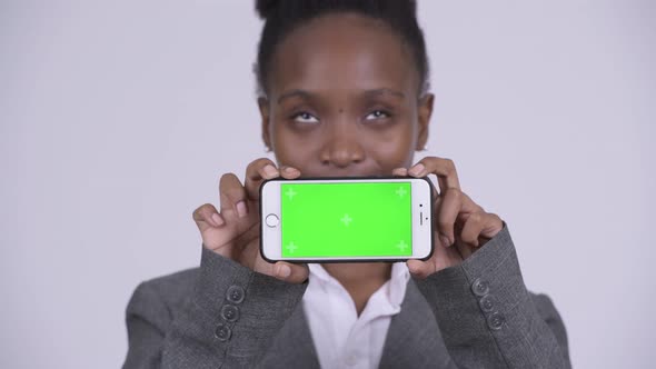 Face of Young Happy African Businesswoman Thinking While Showing Phone