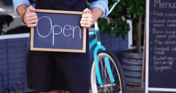 Waiter showing chalkboard with open sign