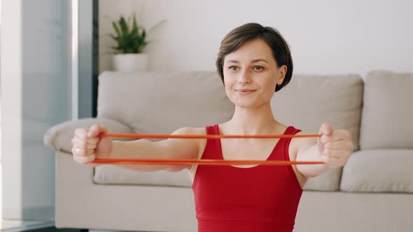 Sporty Woman in Red Costume Doing Exercises with the Fitness Band