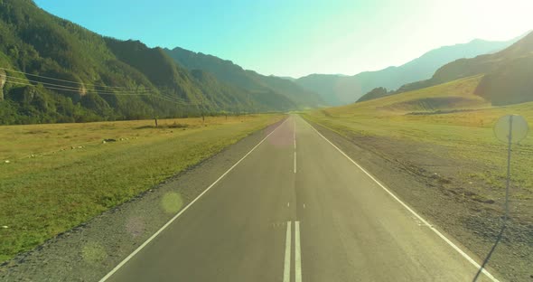 Aerial Low Air Flight Over Mountain Road and Meadow at Sunny Summer Morning