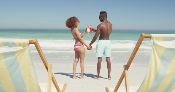 African american couple drinking cocktail seaside