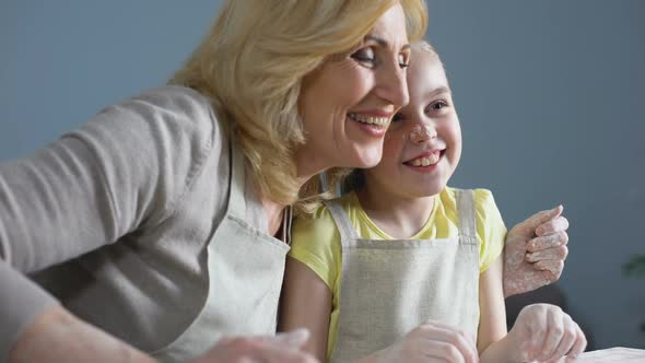 Funny Granddaughter and Her Grandmother Laughing While Cooking at Kitchen