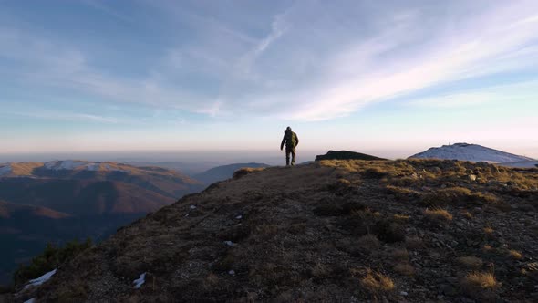 Young man walking on top of the mountain in autumn season with early snow. Standing on the ridge.