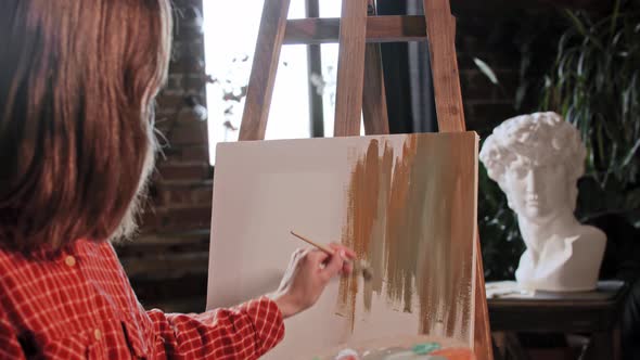 A Young Woman Artist in an Art Workshop  Applying Colors on a Canvas with a Small Brush