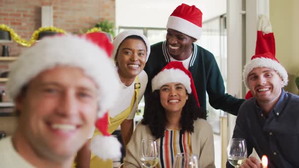 Happy group of diverse friends celebrating meal, taking selfie at christmas time