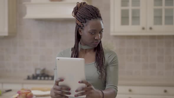 Portrait of African American Young Woman Making Selfie on Tablet on the Background of Modern Kitchen