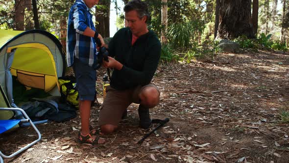 Father teaching son to use trekking pole outside tent