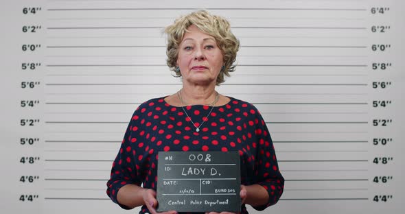 Portrait of Elderly Woman with Blond Hair Holding Sign for Photo in Police Department