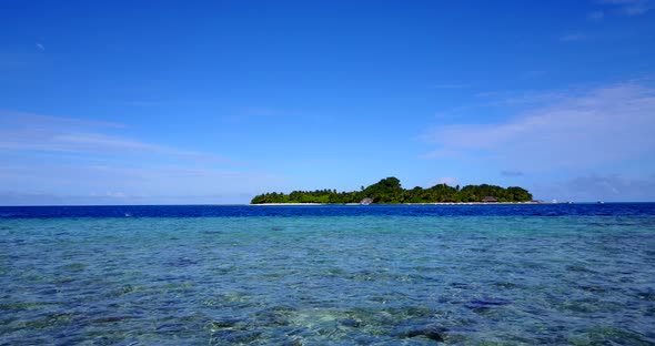 An Island In Fiji - Clear Shallow Ocean Water With Lush Island In The Background - Wide Shot