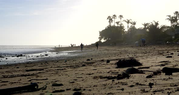 A surfer running along the beach to Rincon point in California to paddle out and catch a wave as the