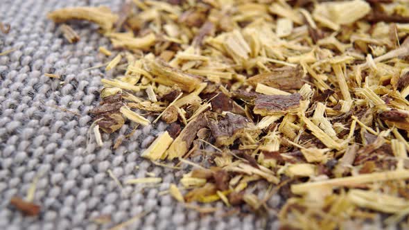 Dried crushed Liquorice root on a rough rustic jute cloth. Macro. Rotation