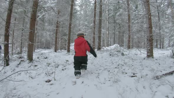 A child runs through a snowy forest to catch up with their parent