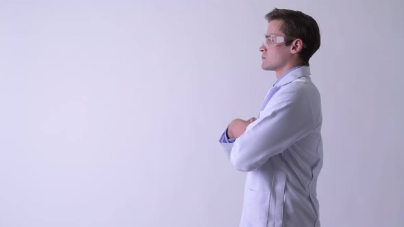 Profile View of Young Happy Handsome Man Doctor Wearing Protective Glasses with Arms Crossed