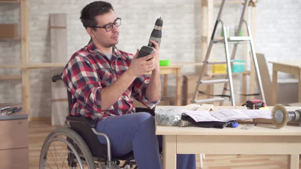 Portrait of a Disabled Man in a Wheelchair with Electric Screwdriver in Hand