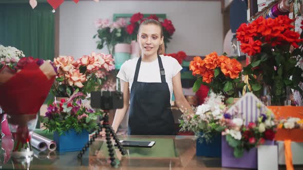 Female Florist Discusses the Order By Talking on Video Call Using a Smartphone in a Flower Shop