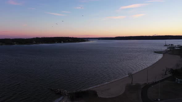 an aerial shot over an empty park looking at the bay during a beautiful sunrise. The sky is pink and