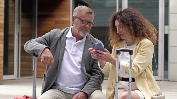 Beautiful Mature Couple with Suitcases is Sitting on a Bench Waiting for Their Flight