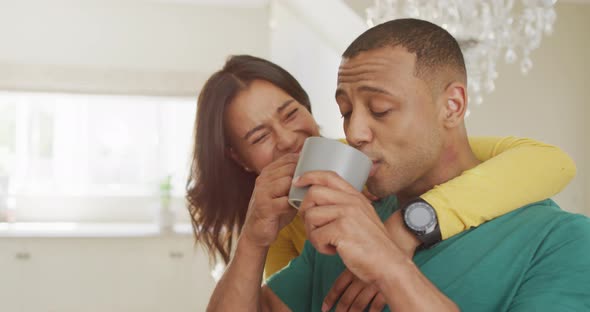 Happy biracial couple with coffee talking and embracing