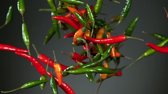 Super Slow Motion Shot of Mixed Chilli Side Colision on Dark Grey Background at 1000Fps.