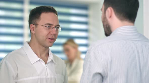 Confident Male Doctor Talking To Male Patient