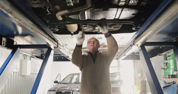 Smiling Mature Mechanic Man In A Car Service. Portrait Under The Car