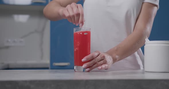 Woman's Hand Stirs Bcaa in a Glass Water Turns Red