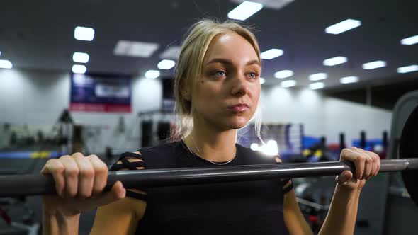 Fit woman holding barbell in gym