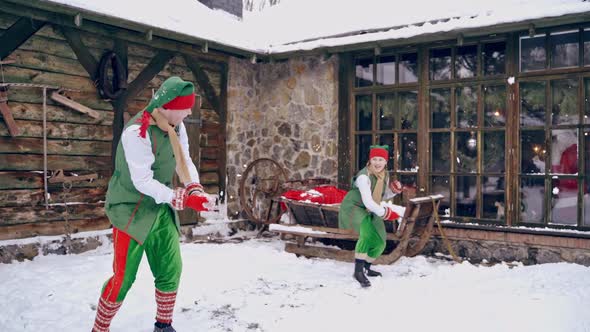 Couple of elves are playing snowballs running aroud a backyard. Holidays. Christmas eve.