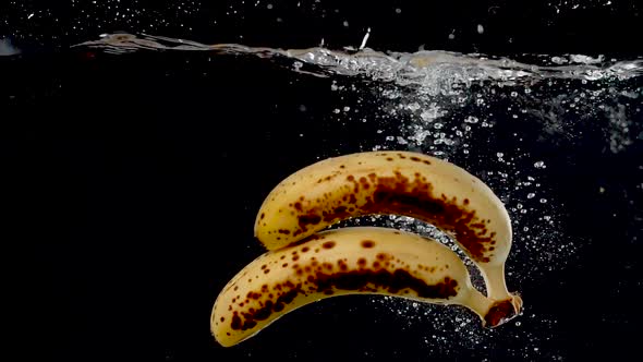 Ripe bananas being dropped into water in slow motion.
