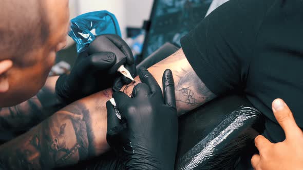 Male Tattoo Artist Tattooing a Client