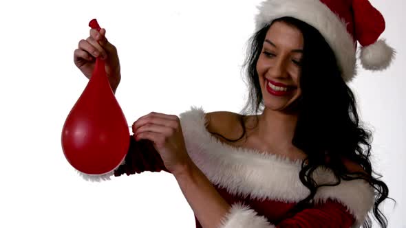 Pretty brunette in santa outfit popping a water balloon