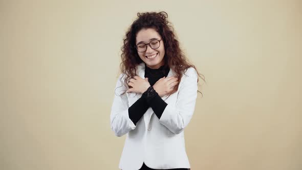 Happy and Excited Young Woman with Curly Hair She Smiles While Holding Her Hands to Her Chest