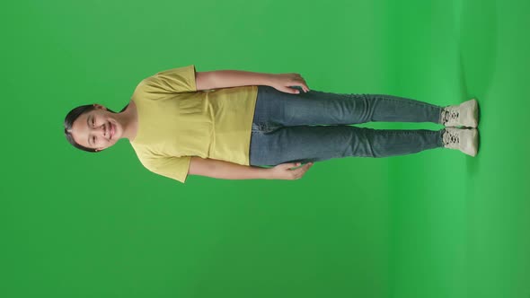 Full Body Of Young Asian Kid Girl Warmly Smiling On Green Screen Background In The Studio