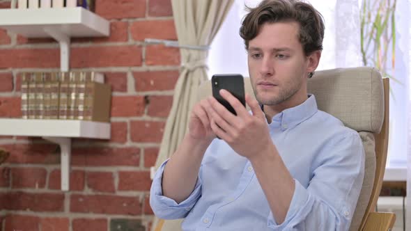 Young Man Celebrating Success on Smartphone